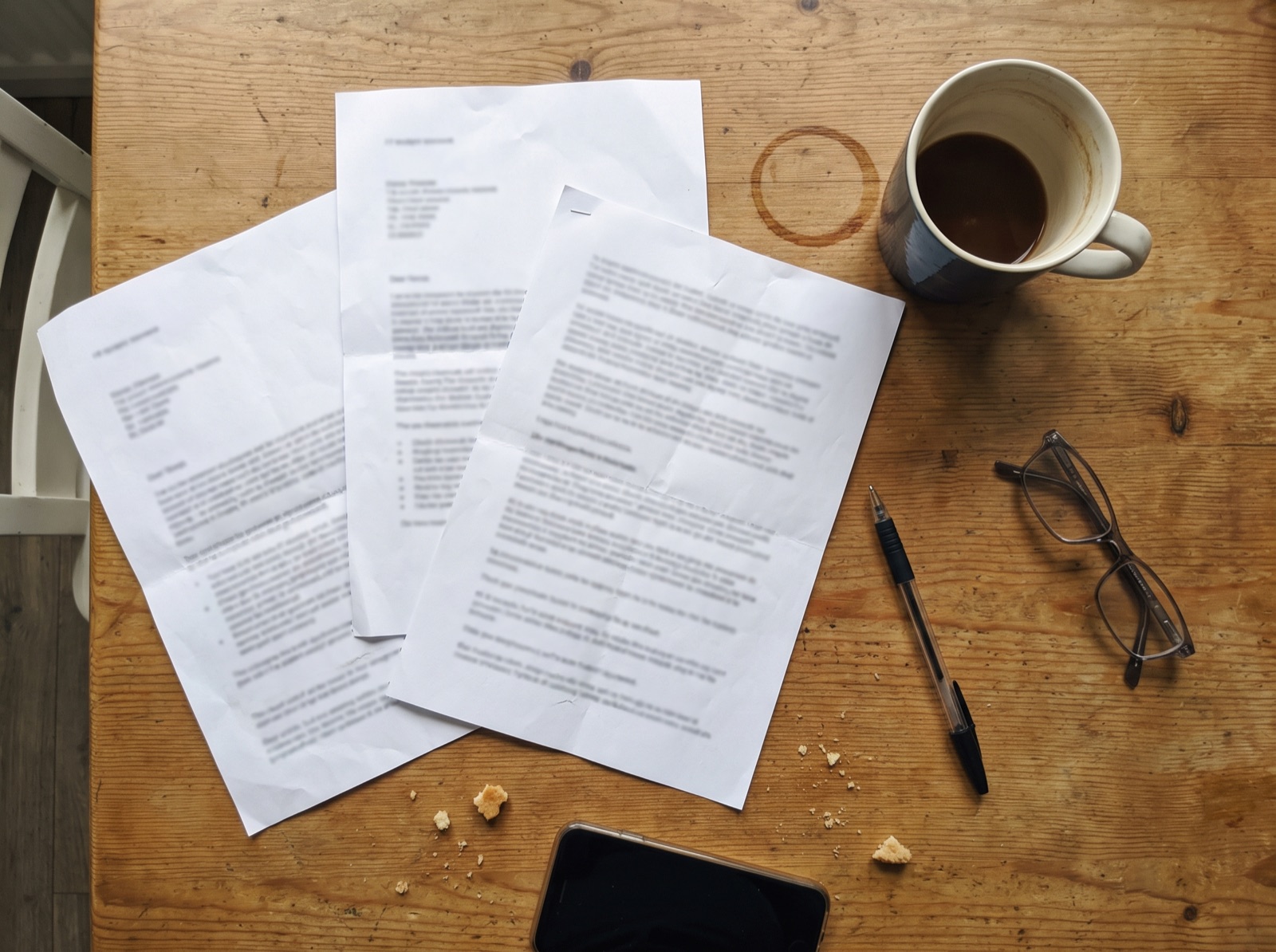 Drie uitgeprinte offertes op een keukentafel, met een pen, een bril en een mok koffie ernaast